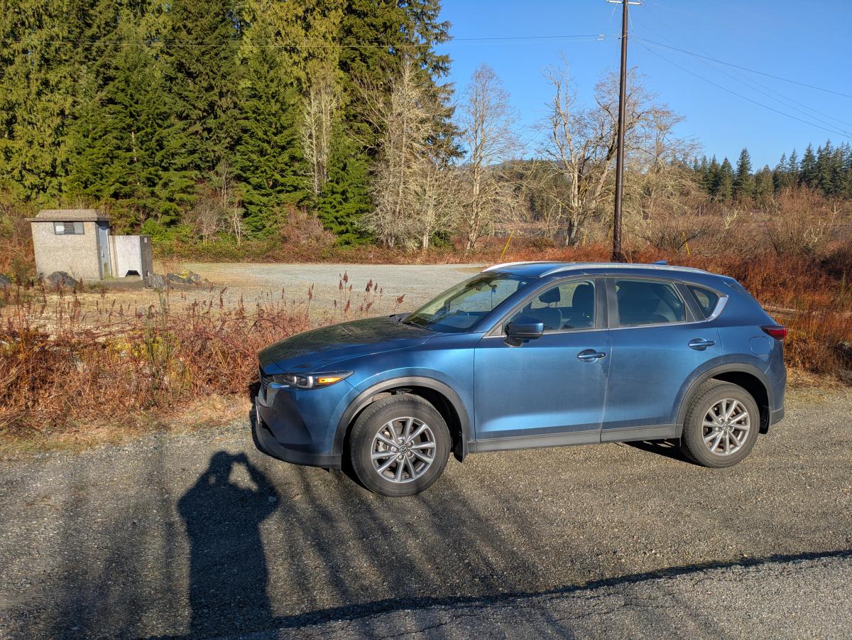 Vehicle on wide road shoulder in front of gravel parking lot