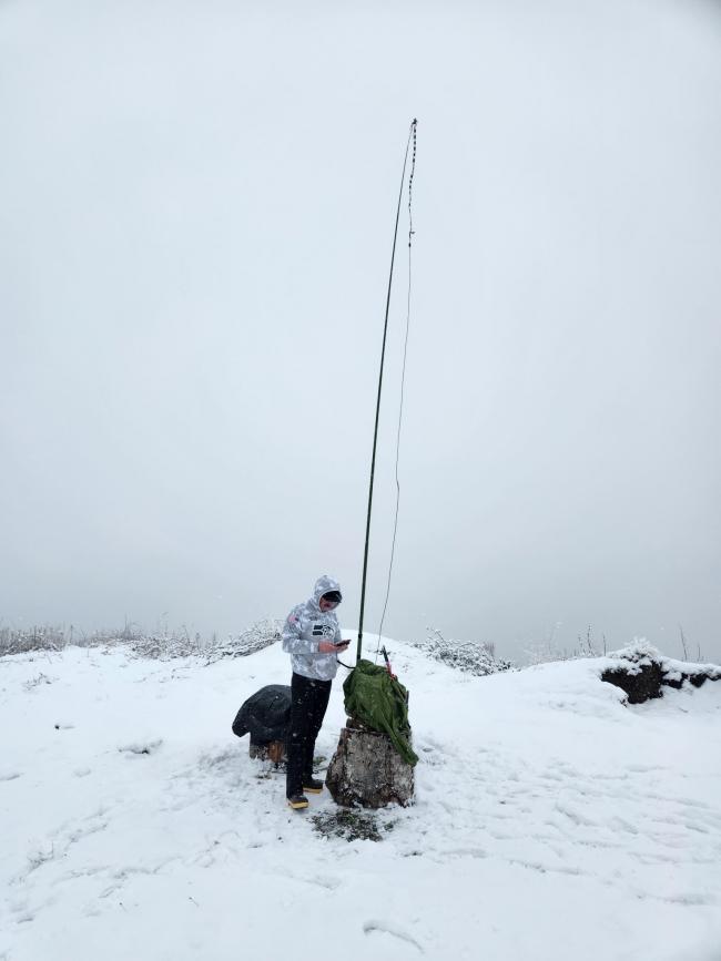 man standing in front of portable ham-radio setup in the snow