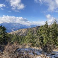 The view to the west on the trail. Trees and mountains are visible.