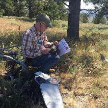 Tim sitting uncomfortably on a narrow downed tree limb